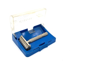 Maquinilla de afeitar Gillette plateada vintage con estuche azul. Decoración retro para tocador de baño o barbería.