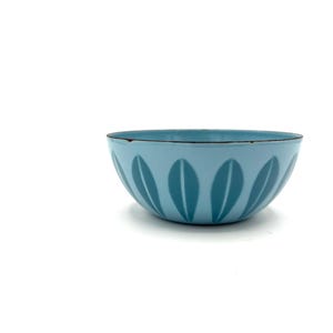 Puede incluir: Un cuenco de color azul claro con un patrón repetitivo de motivos en forma de hoja de color azul más oscuro alrededor del exterior. El cuenco tiene una forma redondeada y lisa con un borde fino de color oscuro en la parte superior.