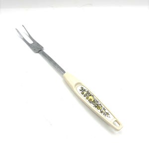 May include: A two-pronged metal fondue fork with a long, slender silver-toned shaft. The handle is made of off-white plastic and features a decorative, repeating botanical pattern in shades of yellow, green, and brown along its center.