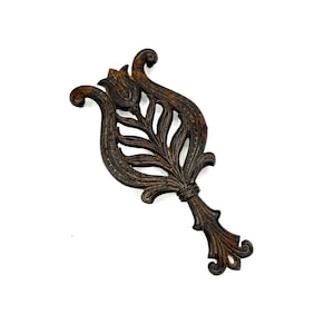 May include: A cast iron pot holder in the shape of a stylized tulip with a brown patina finish.