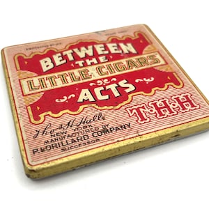May include: Vintage rectangular tin with a red and gold design. The text "BETWEEN THE LITTLE CIGARS ACTS" is prominently displayed. The tin also features the text "The H Hall, New York, Manufactured by P. Lorillard Company, Successor."