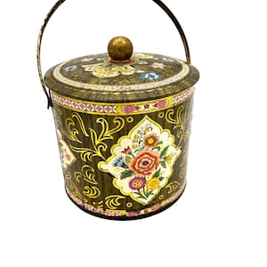 May include: Vintage metal container with a lid and handle. The container is decorated with floral patterns in shades of red, yellow, blue, and white against a dark green background. The lid has a gold knob. The handle is made of metal.