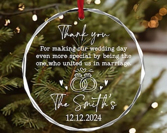 May include: A clear, faceted glass ornament with a red ribbon for hanging. The ornament features white text that reads "Thank you" and a personalized message about a wedding. The date "12.12.2024" is also displayed.