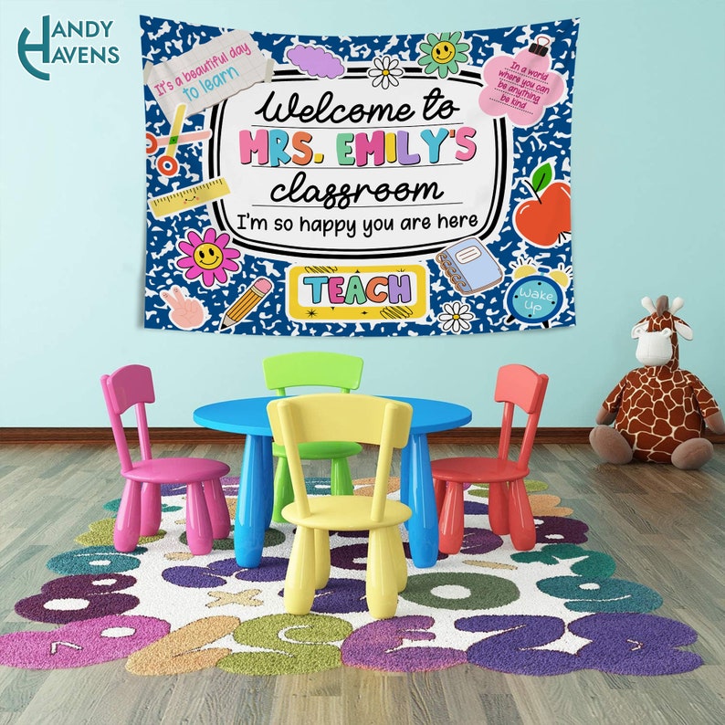 Puede incluir: Un cartel de aula azul y blanco con el texto "Bienvenido a la clase de la Sra. Emily Estoy tan feliz de que est&eacute;s aqu&iacute; Ense&ntilde;ar" con ilustraciones coloridas de un l&aacute;piz, tijeras, una flor, una cara sonriente, un cuaderno, una manzana y un reloj. El cartel est&aacute; colgado en una pared de un aula con una pared azul, un suelo de madera y una alfombra colorida con n&uacute;meros. Hay cuatro sillas peque&ntilde;as y una mesa en la habitaci&oacute;n.