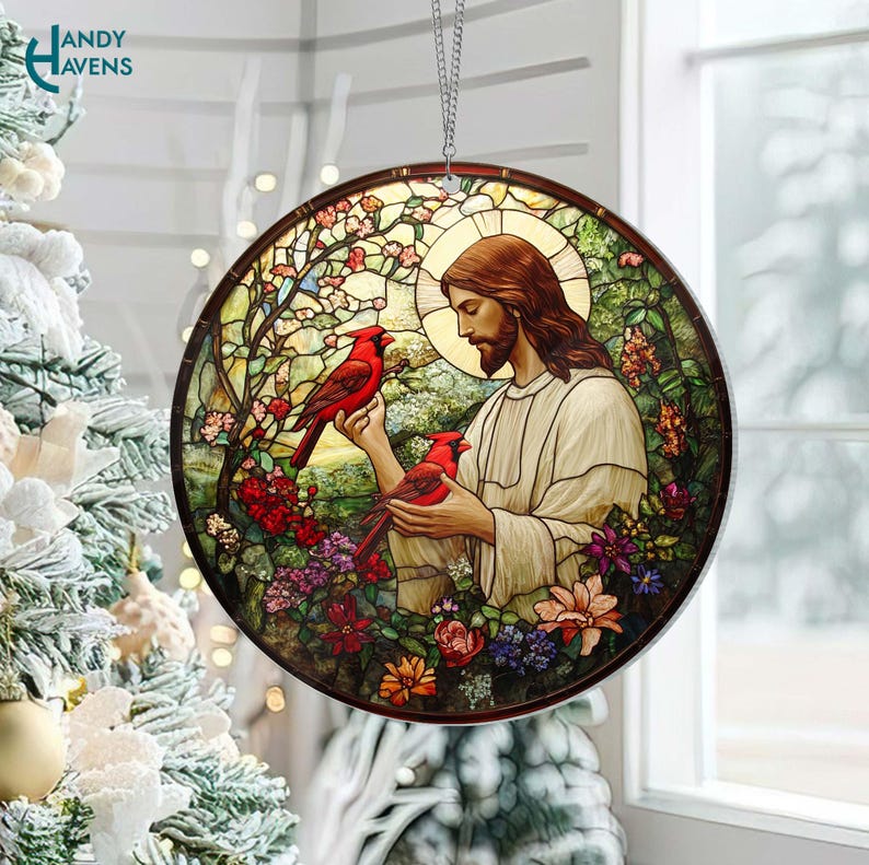 May include: A stained glass ornament with a round shape. The ornament features a colorful floral design with a man in the center. The man is wearing a white robe and has a beard. There are two red cardinals in the image. The ornament has a silver string for hanging.