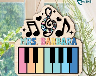 May include: Wooden sign with a musical theme. It features a treble clef, a bass clef, and a musical note. The sign also has a piano keyboard with colorful keys. The text "Mrs. Barbara" is written on the sign.