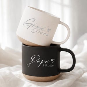 May include: A white ceramic mug with a black handle and the text "But First, Coffee" in a handwritten style. The mug is on a white surface. The mug is 10 cm tall.