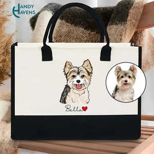 K&ouml;nnte beinhalten: Wei&szlig;e Canvas-Tragetasche mit schwarzen Henkeln und schwarzem Boden. Die Tasche zeigt eine Cartoon-Illustration eines Yorkshire Terriers mit dem Namen "Bella" und einem roten Herzen.