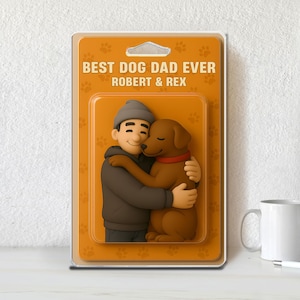 May include: A framed figurine featuring a man hugging a brown dog. The man wears a gray beanie and jacket. The dog has a red collar. The packaging reads "BEST DOG DAD EVER" and "ROBERT & REX".