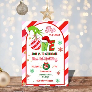May include: A festive invitation for Elsa's 1st birthday, featuring a Grinch-themed design with red and green accents. The invitation includes the text "She is a sweet ONE" and details for the party on December 24th.