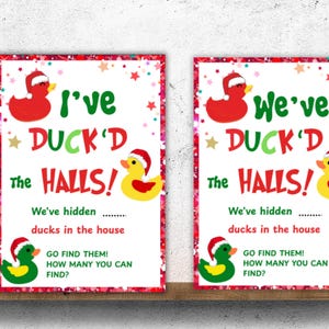 May include: Two Christmas signs with red borders, featuring the text "I've DUCK'D the HALLS!" and "We've DUCK'D the HALLS!". Each sign has red, yellow, and green ducks in Santa hats, with the text "We've hidden ducks in the house."