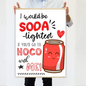 Könnte beinhalten: Ein gerahmter Druck mit dem Text "I would be SODA-lighted if you'd go to HOCO with ME!" in Schwarz und Rot. Auf dem Druck ist eine Cartoon-rote Limonadendose mit einem lächelnden Gesicht abgebildet, zusammen mit einem roten Herzen und einem Stern.