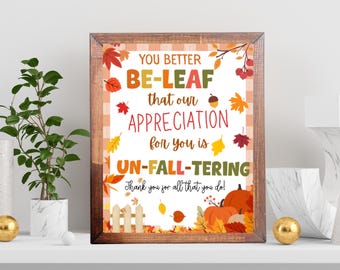 Puede incluir: Un estampado enmarcado con temática otoñal con el texto "YOU BETTER BE-LEAF that our APPRECIATION for you is UN-FALL-TERING. Thank you for all that you do!" La obra presenta hojas de otoño, calabazas y un marco de madera.