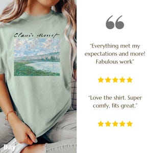 May include: A light green t-shirt with a painting of a river and trees. The text "Claude Monet" is printed on the shirt. The shirt is being worn by a person. The text "Everything met my expectations and more! Fabulous work" is printed below the image. Five yellow stars are shown below the text. The text "Love the shirt. Super comfy, fits great." is printed below the stars. Five yellow stars are shown below the text.