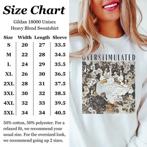 May include: White Gildan 18000 Unisex Heavy Blend Sweatshirt with the word "OVERSTIMULATED" above a graphic of ducks and flowers. The image includes a size chart with measurements in inches for width, length, and sleeve.
