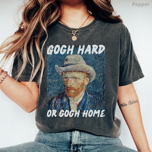 May include: A dark gray t-shirt with a vintage look featuring a painting of Vincent van Gogh and the text "Gogh Hard or Gogh Home".