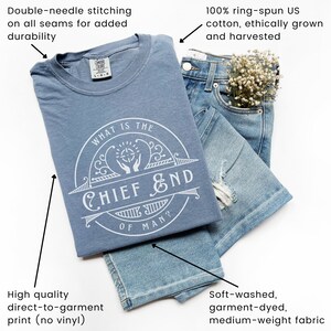May include: A blue t-shirt with a white circle graphic that says "What is the Chief End of Man?" The shirt is made of 100% ring-spun US cotton and features double-needle stitching on all seams.