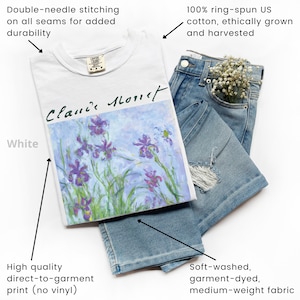 May include: White t-shirt with a print of a painting by Claude Monet, featuring purple irises on a light blue background. The text "Claude Monet" is written in black cursive on the print. The t-shirt is made of 100% ring-spun US cotton and has double-needle stitching on all seams.