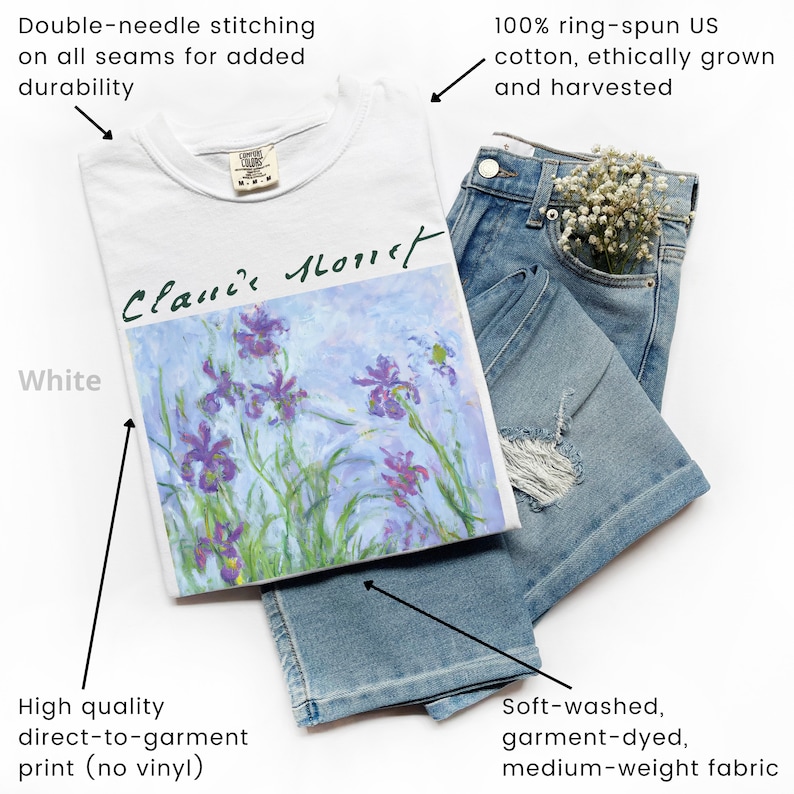 May include: White t-shirt with a print of a painting by Claude Monet, featuring purple irises on a light blue background. The text "Claude Monet" is written in black cursive on the print. The t-shirt is made of 100% ring-spun US cotton and has double-needle stitching on all seams.