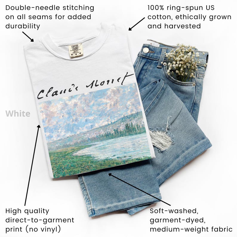 May include: White t-shirt with a painting of a river and mountains. The text "Claude Monet" is written in black ink on the shirt. The shirt is made of 100% ring-spun US cotton and is double-needle stitched for durability.