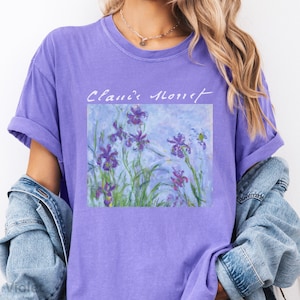 May include: Purple t-shirt with a painting of purple irises and the text "Claude Monet" printed on the front.