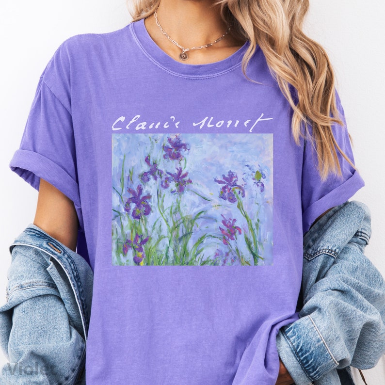 May include: Purple t-shirt with a painting of purple irises and the text "Claude Monet" printed on the front.