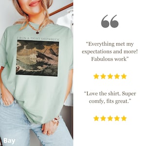 May include: A light green t-shirt with the text "I RUN A TIGHT SHIPWRECK" above a vintage illustration of a ship in a storm. The shirt is paired with light blue jeans.