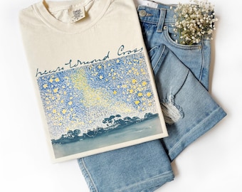 May include: A cream coloured t-shirt with a blue and yellow starry night painting and the text "bears tremendous cross" in black script.