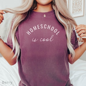 May include: A mauve colored t-shirt with the text "HOMESCHOOL is cool" in white lettering.