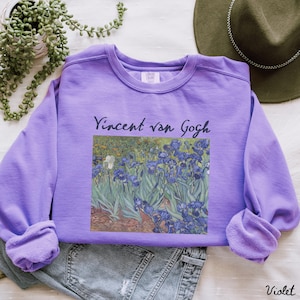 May include: A purple sweatshirt with a print of Vincent van Gogh's Irises painting. The text "Vincent van Gogh" is printed above the painting.