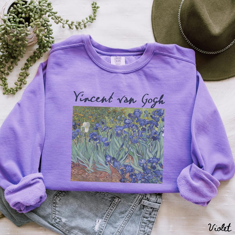 May include: A purple sweatshirt with a print of Vincent van Gogh's Irises painting. The text "Vincent van Gogh" is printed above the painting.