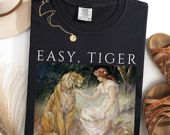 May include: Black crew neck sweatshirt with the text "EASY, TIGER" above a painting of a woman and a tiger. A gold necklace and brown sandals are next to the shirt. The shirt is a Comfort Colors XL-TG-EG.