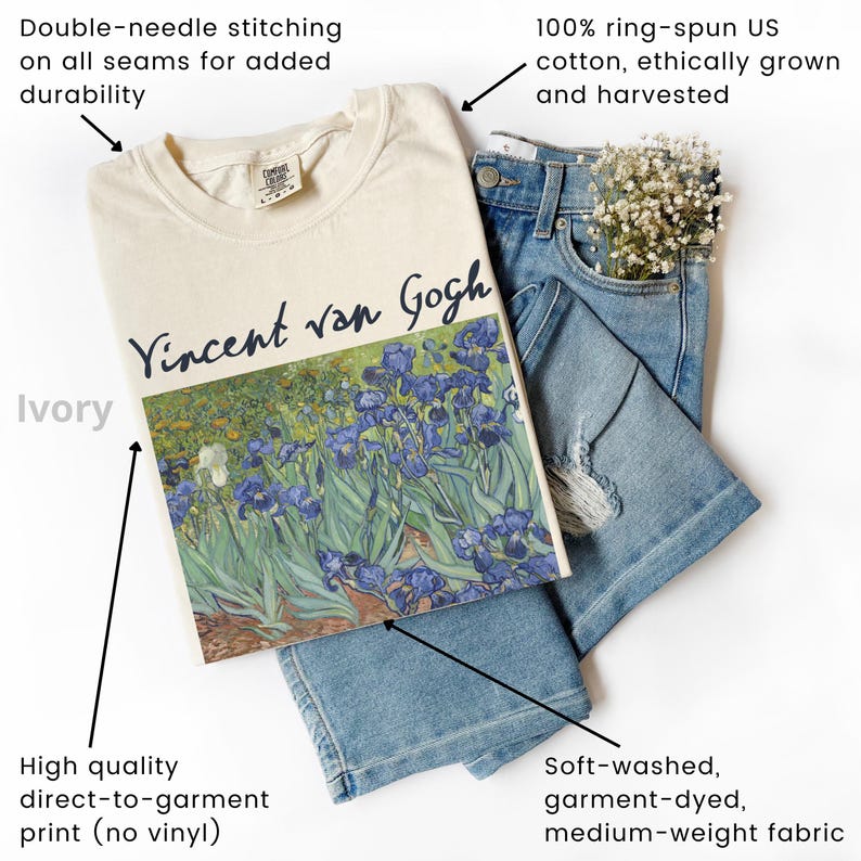 May include: An ivory t-shirt featuring a graphic print of Vincent van Gogh's Irises painting, paired with blue denim jeans. The shirt displays the artist's name in dark blue script above the floral artwork, showcasing double-needle stitching.
