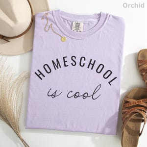May include: A lavender colored t-shirt with the text "HOMESCHOOL is cool" printed on the front.