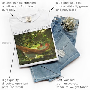 May include: A white t-shirt with the text "ONE MORE CHAPTER" and a graphic of a person in a hammock. The shirt is paired with light blue denim jeans. The shirt is made of 100% ring-spun US cotton and has double-needle stitching.