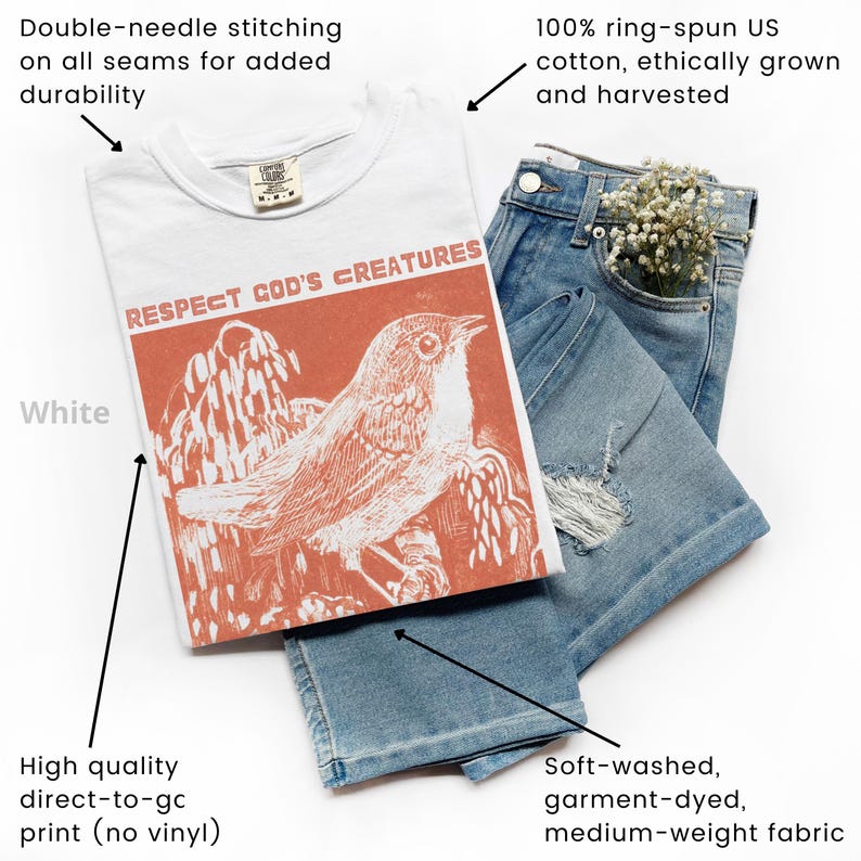 May include: White t-shirt with the text "RESPECT GOD'S CREATURES" and an orange bird graphic. The shirt is paired with light blue denim jeans. The t-shirt is made of 100% ring-spun cotton and has double-needle stitching.