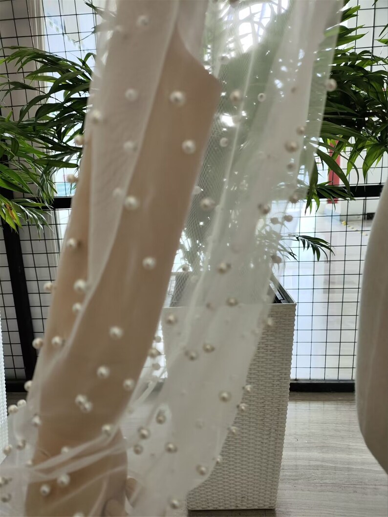 Peut inclure: Tissu blanc transparent avec des perles. Le tissu est drap&eacute; sur un panier en osier blanc.