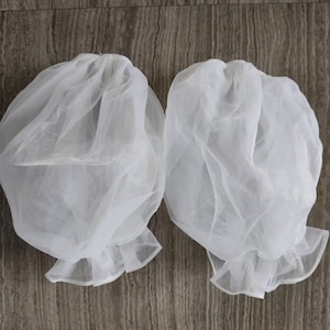 May include: Two white tulle fabric puff sleeves with ruffled edges.