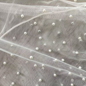 Peut inclure: Tulle blanc avec des perles blanches &eacute;parpill&eacute;es.