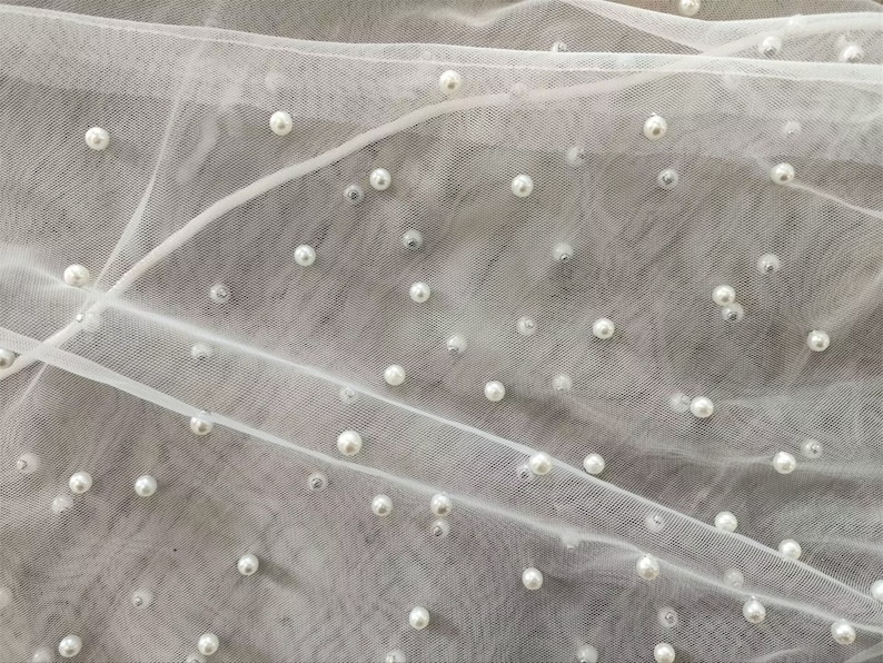 Peut inclure: Tulle blanc avec des perles blanches &eacute;parpill&eacute;es.