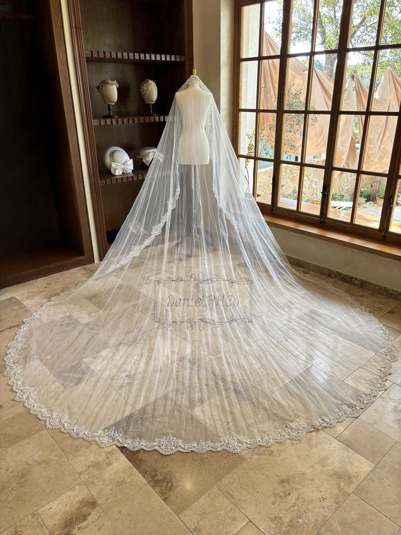 Puede incluir: Un velo de novia blanco con un delicado borde de encaje y un borde festoneado. El velo est&aacute; hecho de tul suave y est&aacute; dise&ntilde;ado para fluir con gracia detr&aacute;s de la novia.