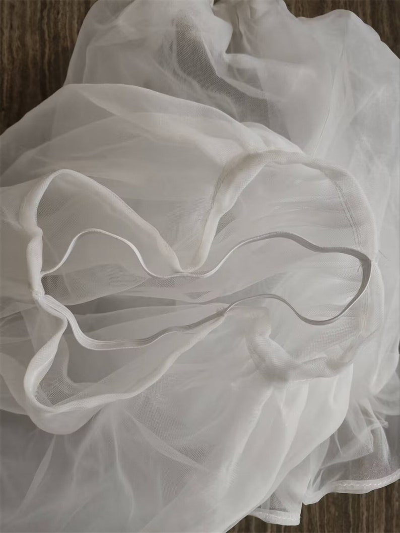 May include: White tulle fabric with a gathered edge. The fabric is soft and sheer, and it is perfect for making a variety of garments and accessories.