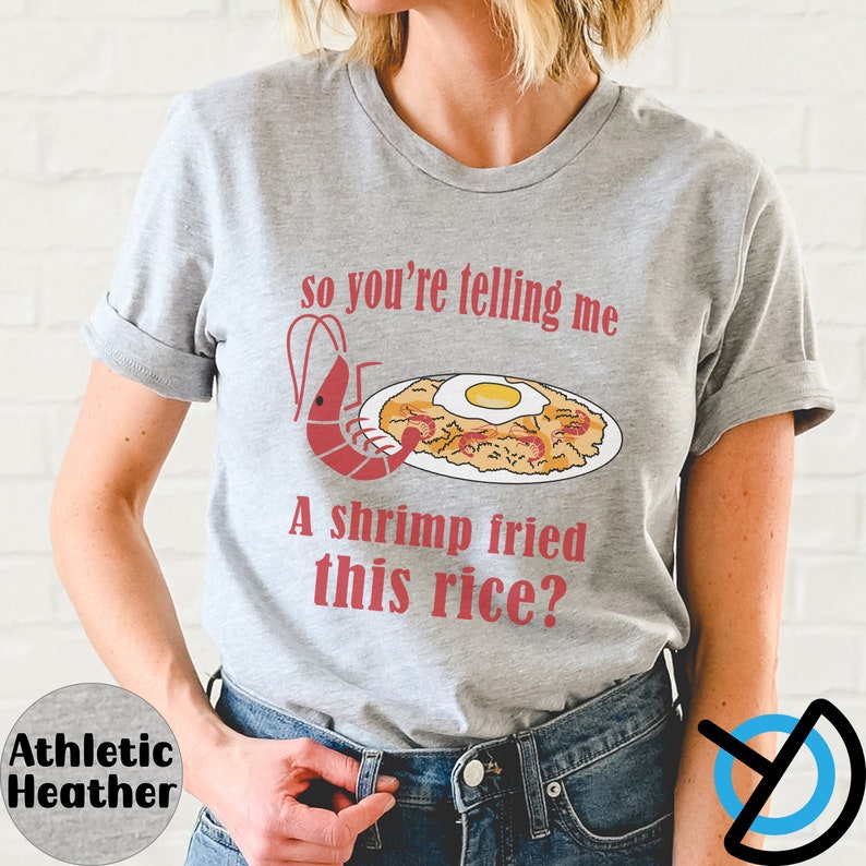 May include: A gray t-shirt with the text "so you're telling me a shrimp fried this rice?" and an illustration of a shrimp and a plate of fried rice with an egg on top.