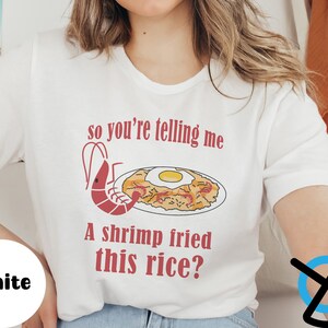 May include: White t-shirt with a red graphic of a shrimp and fried rice with the text "so you're telling me a shrimp fried this rice?"