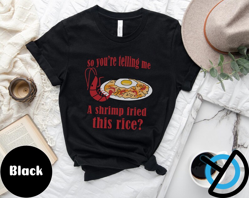 May include: Black t-shirt with a red shrimp and fried rice illustration. The text on the shirt reads "so you're telling me a shrimp fried this rice?"