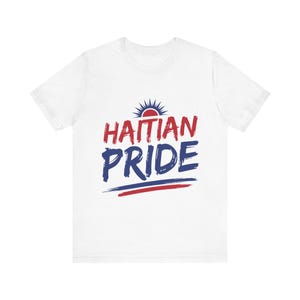 May include: White t-shirt with the words "HAITIAN PRIDE" in red and blue brushstroke lettering. A sunburst graphic sits above the word "HAITIAN". Two horizontal lines, red and blue, are below the word "PRIDE".