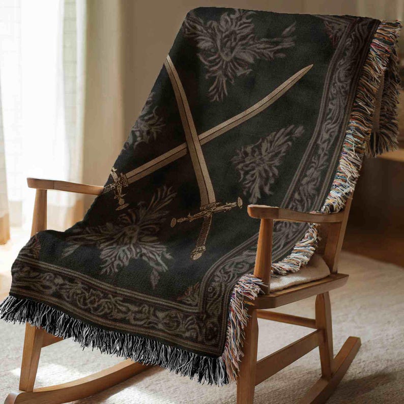 A black and gray patterned blanket with a sword design is draped over a wooden rocking chair.