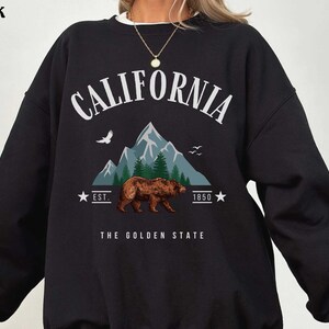 a woman wearing a black sweatshirt with a bear on it