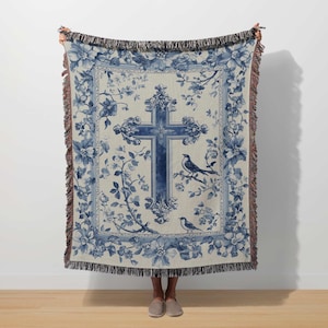 a woman holding a blue and white tapestry with a cross on it
