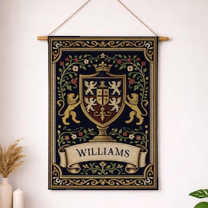 Könnte beinhalten: Ein marineblaues Wandbehang mit einem Familienwappen-Design. Das Wappen zeigt einen Schild mit einer Krone, Löwen und floralen Akzenten. Der Name "WILLIAMS" wird auf einem Banner darunter angezeigt.